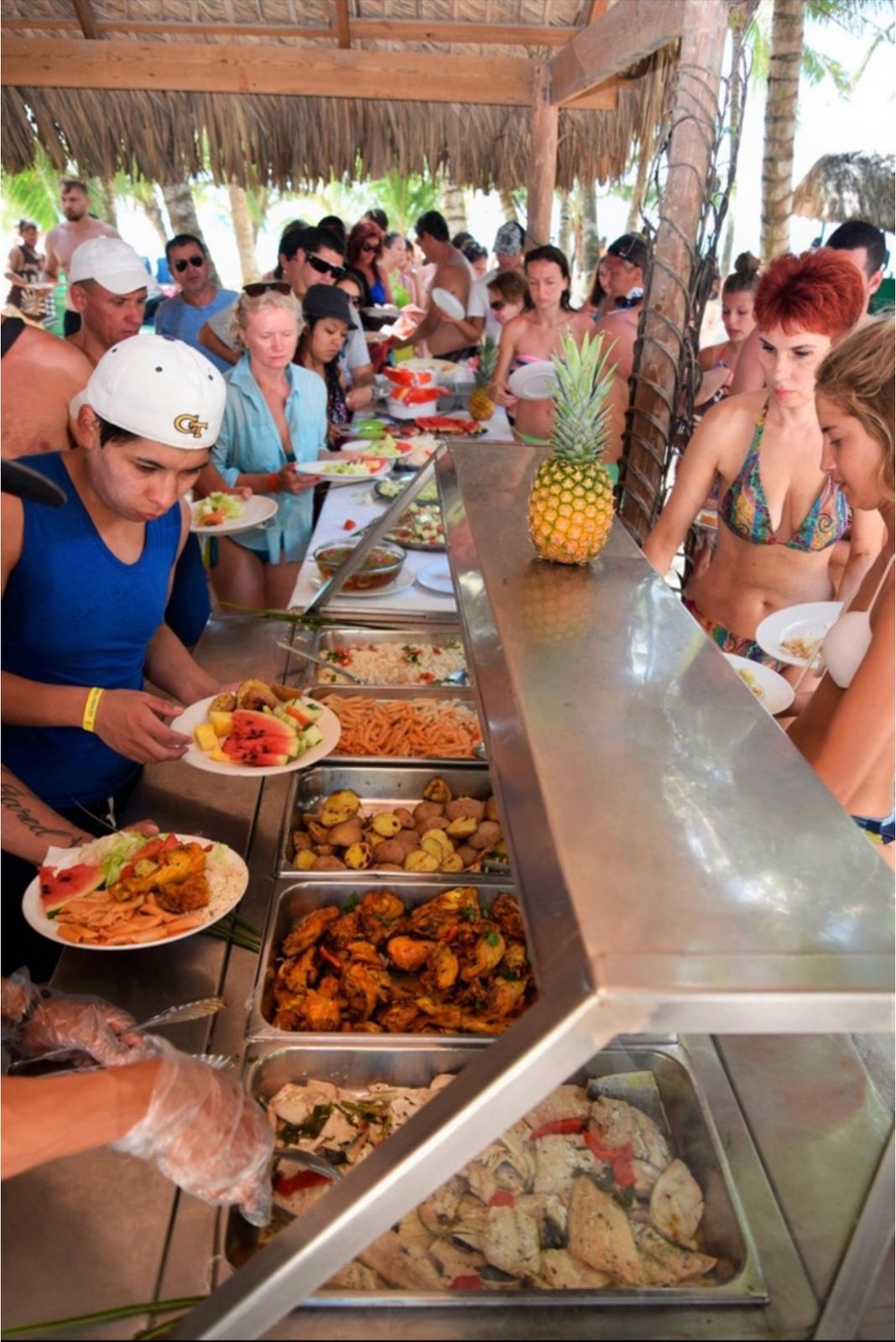 Buffet de almuerzo tropical bajo techo de palapa con comida dominicana